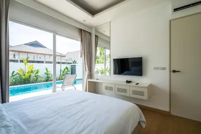 a bedroom with a bed and a tv and a window at Deluxe pool villa at Kamala Garden View in Kamala Beach