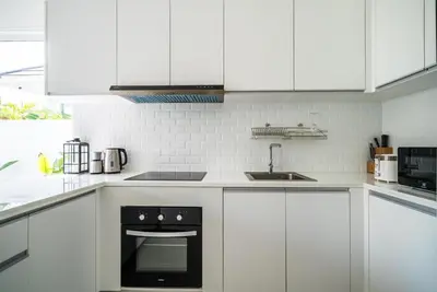 a kitchen with white cabinets and a black oven at Deluxe pool villa at Kamala Garden View in Kamala Beach