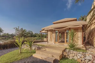 a small building with a porch and a stone wall at Aladdin Luxury Camp Phuket in Phuket Town