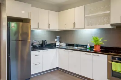 a kitchen with white cabinets and a stainless steel refrigerator at Laguna Luxury 2-Bed Pool Villa - Near Layan Beach in Layan Beach