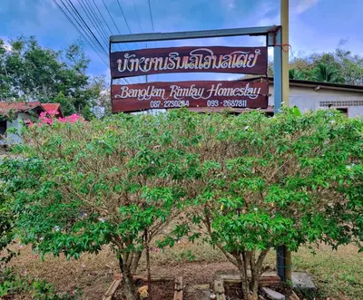 a sign for a restaurant next to two trees at Bang Yan Rimlay in Ko Yao Noi