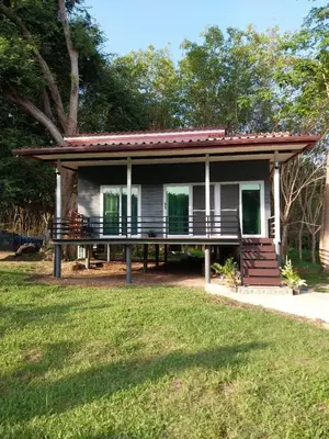 a small house with a porch and a grass field at Bang Yan Rimlay in Ko Yao Noi