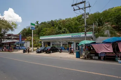 a street with cars parked in front of a store at mona seaview pool villa beach front AoYon Beach in Panwa Beach