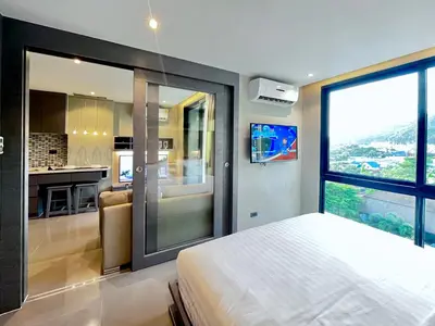 a bedroom with a bed and a view of a kitchen at Kamala Beach D68 Exclusive Junior Suite in Kamala Beach