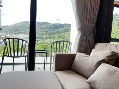 a living room with a couch and a large window at Kamala Beach D68 Exclusive Junior Suite in Kamala Beach