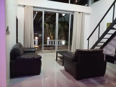 a living room with two chairs and a staircase at Villa B23 Phuket in Nai Yang Beach