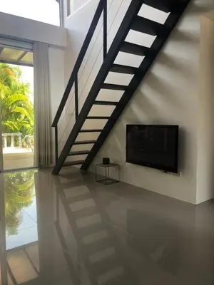 a living room with a staircase and a flat screen tv at Villa B23 Phuket in Nai Yang Beach