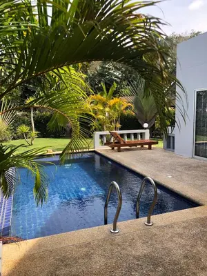 a swimming pool with a bench in front of a house at Villa B23 Phuket in Nai Yang Beach