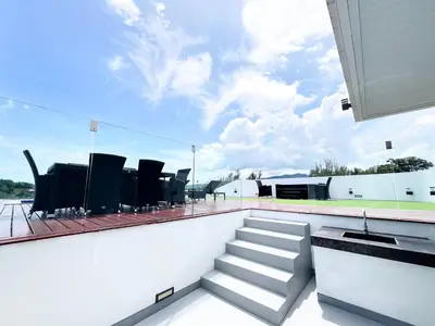 a balcony with chairs and stairs on a roof at Twin Sands Resort Penthouse in Patong Beach