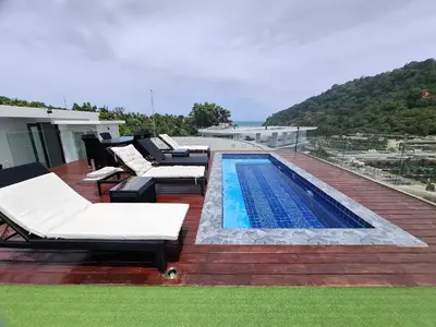 a deck with a swimming pool and lounge chairs next to at Twin Sands Resort Penthouse in Patong Beach