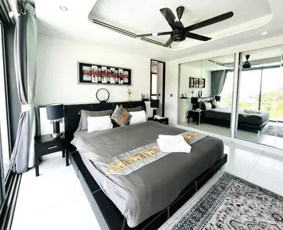 a bedroom with a large bed with a ceiling fan at Twin Sands Resort Penthouse in Patong Beach