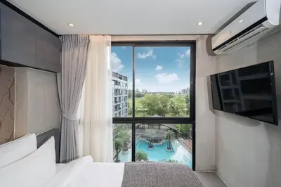 a bedroom with a large window with a view of a pool at Tropics Kamala 2BR Apartment CTG B605-6 in Kamala Beach