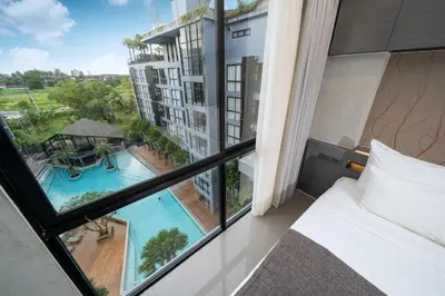 a bedroom with a view of a pool from a window at Tropics Kamala 2BR Apartment CTG B605-6 in Kamala Beach