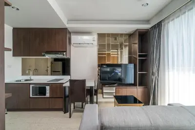 a kitchen and living room with a table and a tv at Private apartment at Aristo Resort by Lofty in Surin Beach