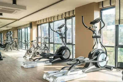 a row of exercise bikes in a gym with windows at Private apartment at Aristo Resort by Lofty in Surin Beach