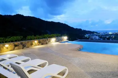 a group of white lounge chairs next to a swimming pool at Kata Ocean View Luxury condo & Seaview K12 in Kata Beach