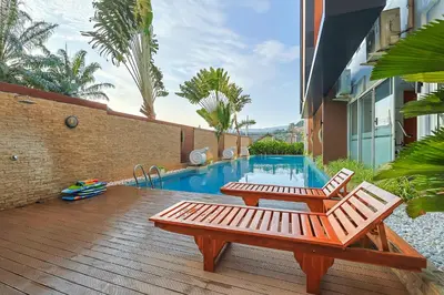 a wooden deck with two benches and a swimming pool at Sunset Residence Karon Beach in Karon Beach