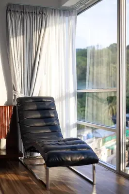 a leather chair sitting in front of a large window at Sunset Residence Karon Beach in Karon Beach