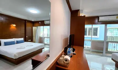 a bedroom with a bed and a desk with a television at Chalita House in Patong Beach