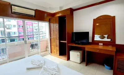 a bedroom with a bed and a television and a window at Chalita House in Patong Beach