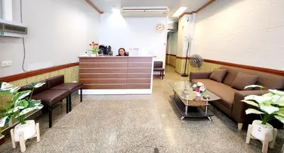 a waiting room with couches and a woman at a counter at Chalita House in Patong Beach