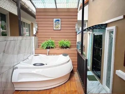 a bathroom with a large white bath tub next to a house at The Phuket Pool Villa in Phuket Town