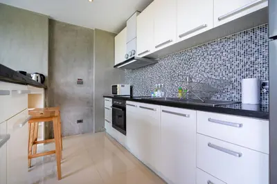 a kitchen with white cabinets and a black counter top at Villa Natural Touch A3 in Kamala Beach