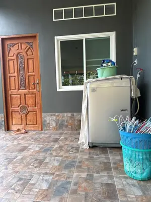 a refrigerator in a room with a door and a basket at Thanid House in Ban Nai Khlong