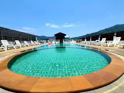 a large swimming pool with chairs and a gazebo at Issara Patong Beach in Patong Beach