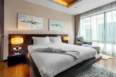 a bedroom with a large bed and a chair at \u3010\u8d85\u503c\u30112\u5367\u5ba4\u522b\u5885\u3010\u5bbd\u655e\u8212\u9002\u301113\u7c73\u957f\u79c1\u5bb6\u6cf3\u6c60\uff0c\u914d\u5957\u9f50\u5168\u51fa\u884c\u65b9\u4fbf700\u7c73\u5230kamala\u6d77\u6ee9 in Phuket Town