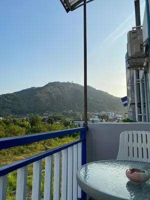 a table on a balcony with a view of a mountain at Kata Sea Blue in Kata Beach