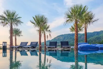 a swimming pool with palm trees and lounge chairs at Tropics Kamala Pool View Studio CTG B608 in Kamala Beach