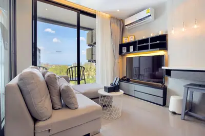 a living room with a couch and a large window at Tropics Kamala Pool View Studio CTG B608 in Kamala Beach
