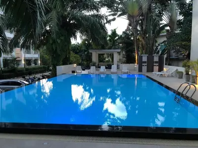 a large blue swimming pool with white chairs and palm trees at Royal Kamala - Peaceful Private Rooftop Pool Apartment in Kamala in Kamala Beach