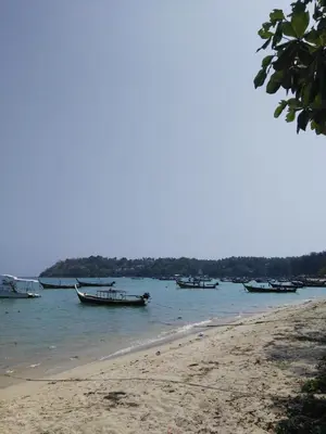 a group of boats in the water on a beach at The Title Rawai West Wing Pool View Suite in Rawai Beach