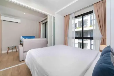 a white bedroom with a large bed and a window at Diamond Apartments Phuket Bangtao in Phuket Town