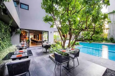 a patio with tables and chairs and a swimming pool at Diamond Apartments Phuket Bangtao in Phuket Town