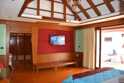 a bedroom with a tv on a red wall at VILLA SIRINTHARA in Rawai Beach