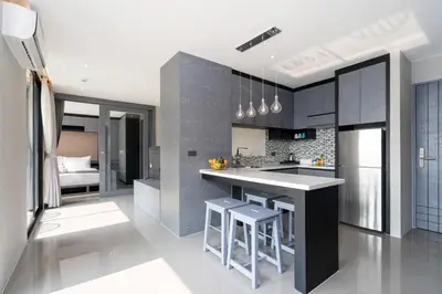 a kitchen with a counter and some stools in it at Tropics Kamala 2BR Pool View Apartment CTG B705-6 in Kamala Beach