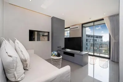 a living room with a white couch and a large window at Tropics Kamala 2BR Pool View Apartment CTG B705-6 in Kamala Beach