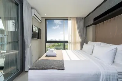 a bedroom with a large white bed and a window at Tropics Kamala 2BR Pool View Apartment CTG B705-6 in Kamala Beach