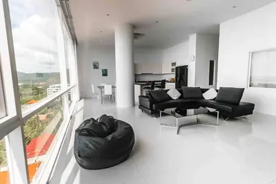 a living room with black furniture and a large window at Large Penthouse 3BR with jacuzzi, Best for Kids in Karon Beach
