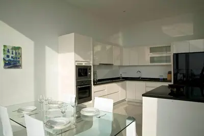 a kitchen with a glass table and white cabinets at Large Penthouse 3BR with jacuzzi, Best for Kids in Karon Beach