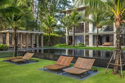 a resort with a swimming pool with chairs and palm trees at Baan Mai Khao by Villacarte in Mai Khao Beach