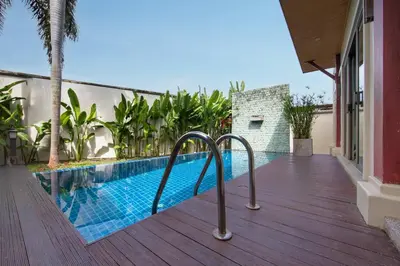 a swimming pool next to a house with a wooden deck at Villa Ikaroa Private pool villa Kokyang Estate in Nai Harn Beach