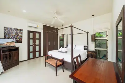 a bedroom with a bed and a table and a tv at Villa Ikaroa Private pool villa Kokyang Estate in Nai Harn Beach