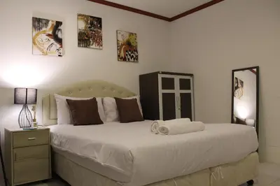 a bedroom with a large white bed and some pictures on the wall at Omaya GuestHouse in Patong Beach