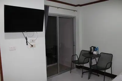 a room with a table and chairs and a television on a wall at Omaya GuestHouse in Patong Beach