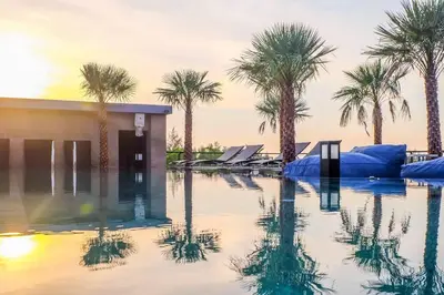a pool of water with palm trees and a building at Kamala D38 Exclusive Junior Suite in Kamala Beach