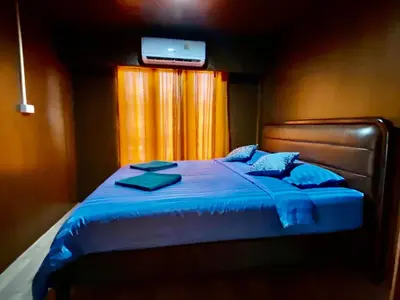 a bedroom with a bed with a television on the wall at Patcharin Homestay in Ban Lo Pla Lai (1)